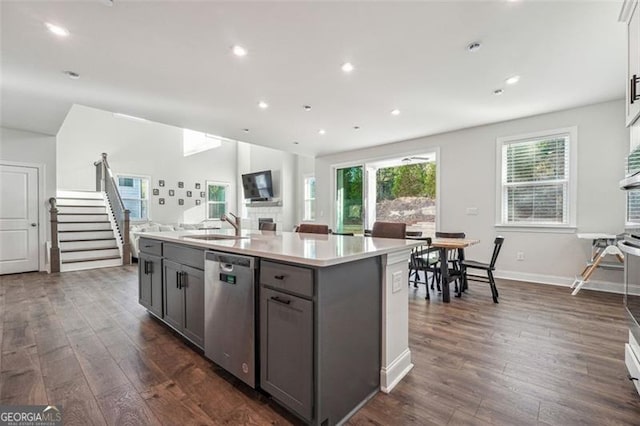 kitchen featuring a center island with sink, dark hardwood / wood-style floors, gray cabinets, sink, and stainless steel dishwasher