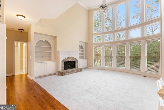 unfurnished living room with built in shelves, a fireplace, wood-type flooring, and plenty of natural light