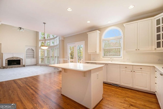 kitchen featuring white cabinetry, light hardwood / wood-style floors, hanging light fixtures, and tasteful backsplash