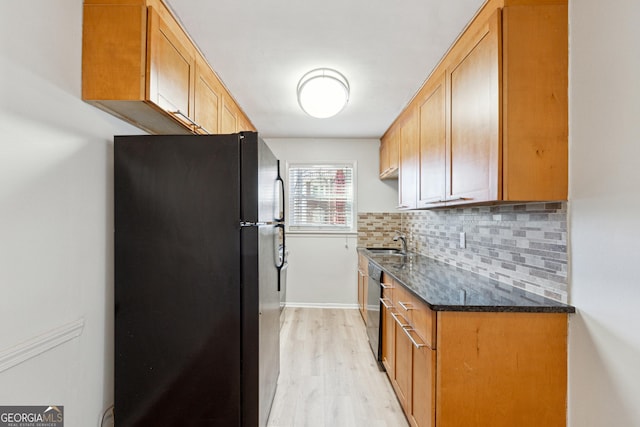 kitchen with tasteful backsplash, sink, dark stone counters, black appliances, and light hardwood / wood-style flooring