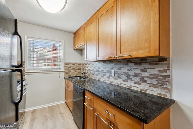 kitchen with sink, dark stone countertops, backsplash, black appliances, and light wood-type flooring