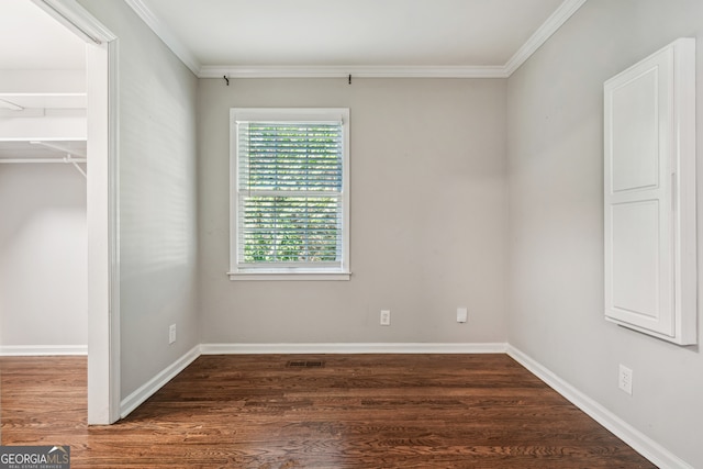 unfurnished bedroom with a walk in closet, crown molding, and dark hardwood / wood-style floors