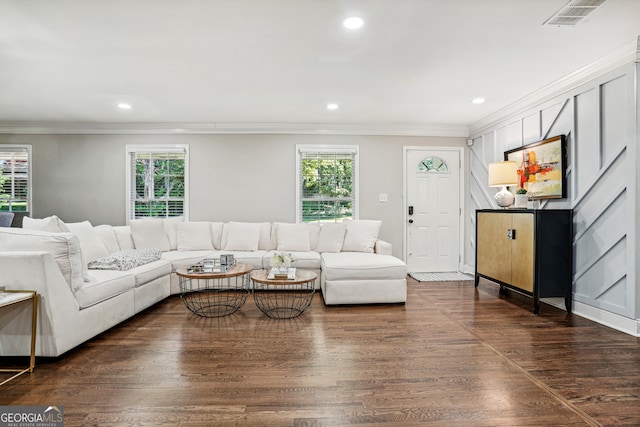 living room featuring dark wood-type flooring, crown molding, and a healthy amount of sunlight