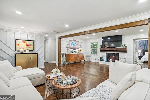 living room with dark hardwood / wood-style floors, ornamental molding, and a brick fireplace