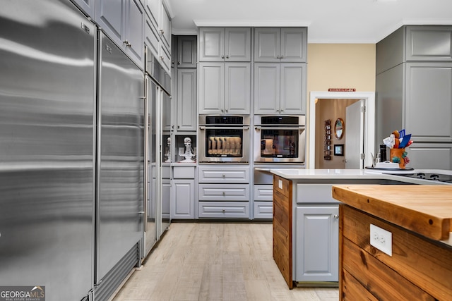 kitchen with gray cabinetry, light hardwood / wood-style floors, and appliances with stainless steel finishes