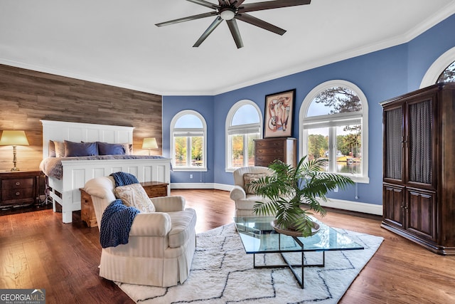 bedroom with hardwood / wood-style flooring, ceiling fan, crown molding, and wood walls