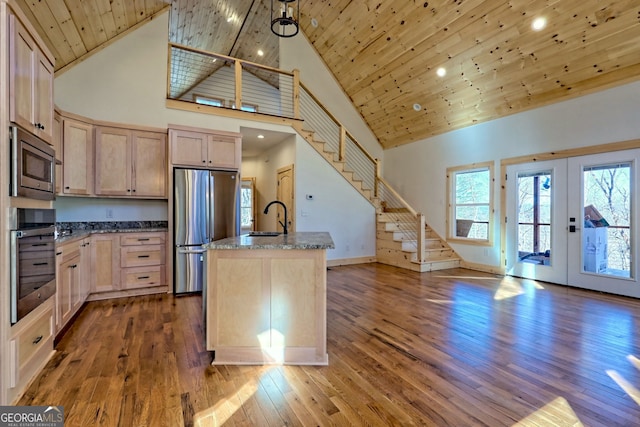 kitchen with a center island with sink, stainless steel appliances, wooden ceiling, light brown cabinetry, and pendant lighting