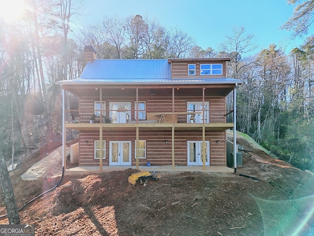 rear view of property featuring a patio area, french doors, and a balcony