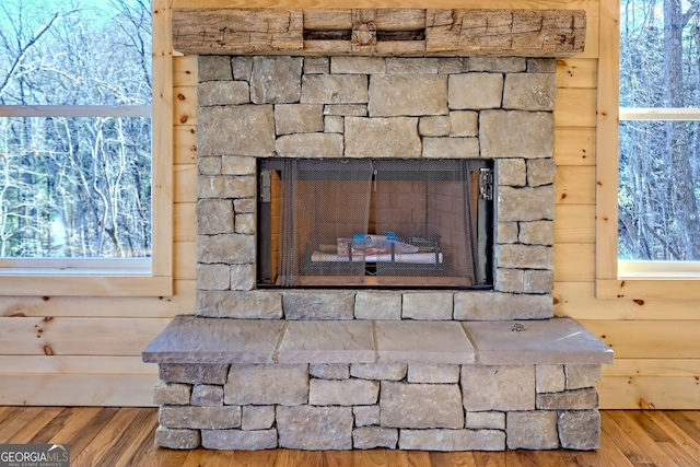 room details with a fireplace, hardwood / wood-style floors, and wooden walls