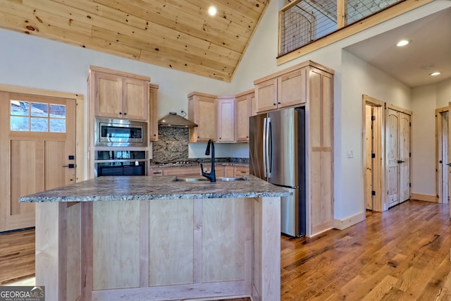 kitchen with appliances with stainless steel finishes, sink, light wood-type flooring, light brown cabinets, and an island with sink