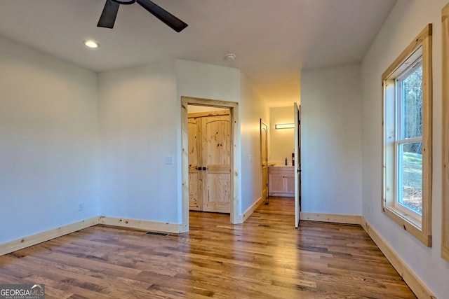 unfurnished bedroom featuring multiple windows, hardwood / wood-style floors, and ceiling fan