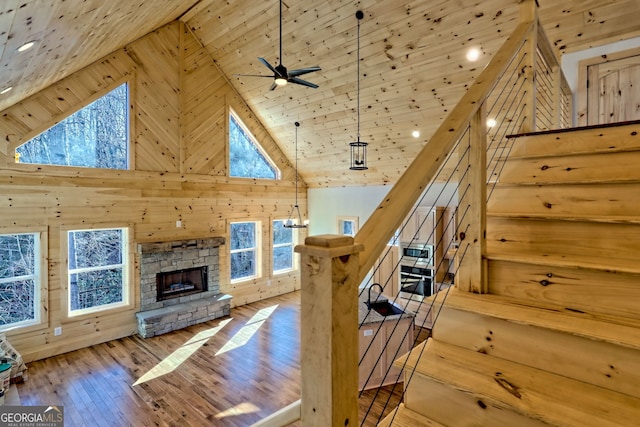 interior space featuring high vaulted ceiling, hardwood / wood-style floors, wooden walls, and a stone fireplace