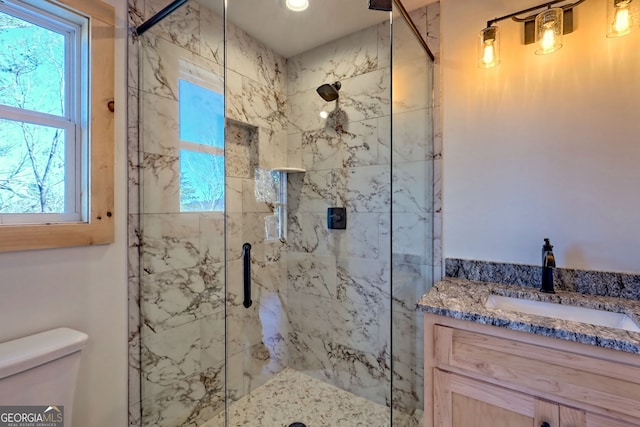 bathroom featuring vanity, a shower with door, and toilet