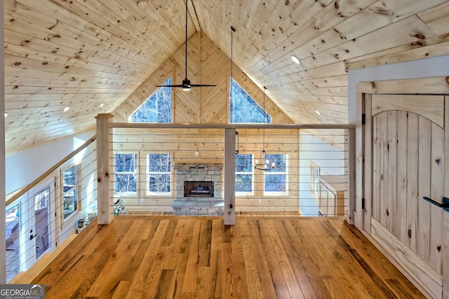 unfurnished living room with wooden ceiling, wood walls, and a fireplace