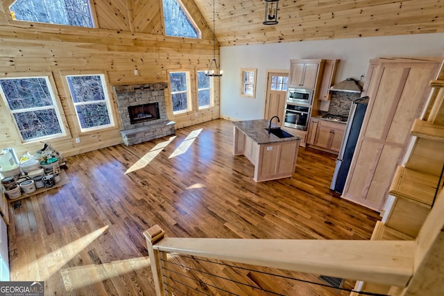 living room with a fireplace, high vaulted ceiling, sink, and hardwood / wood-style floors