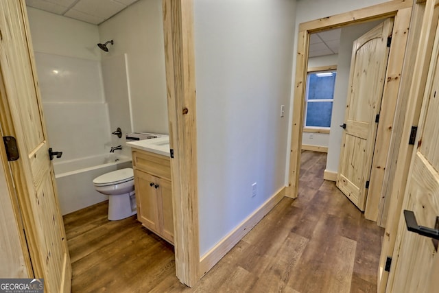 full bathroom with toilet, shower / bathing tub combination, wood-type flooring, and a drop ceiling