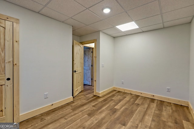 spare room with a paneled ceiling and wood-type flooring