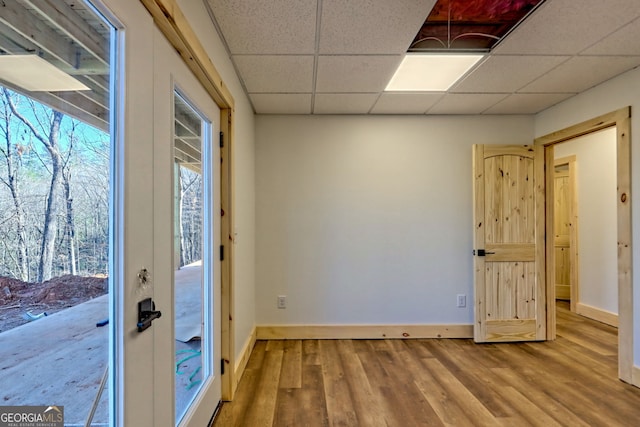 doorway to outside with hardwood / wood-style flooring and a drop ceiling