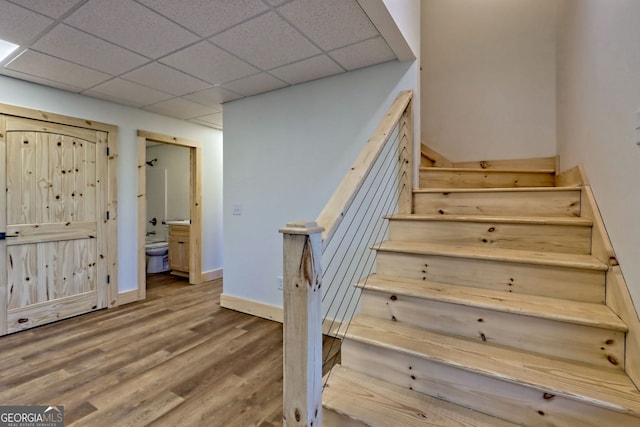 staircase featuring a paneled ceiling and hardwood / wood-style floors