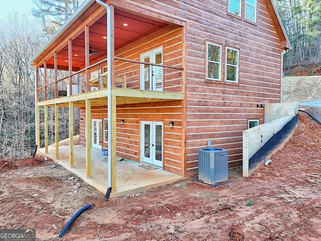 back of property with french doors, central AC unit, a patio, and a balcony