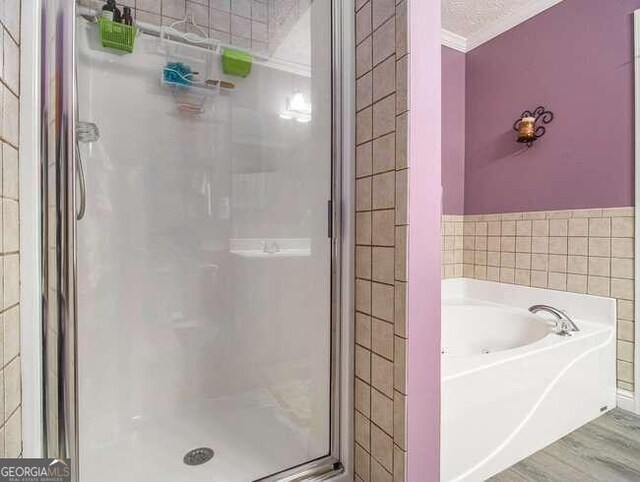 bathroom with wood-type flooring, a textured ceiling, crown molding, and independent shower and bath