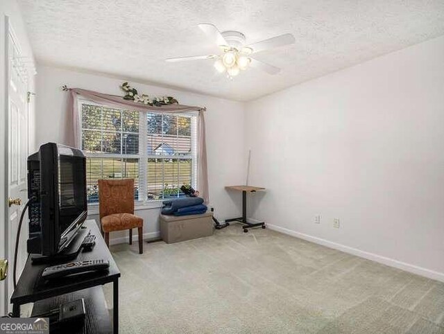 sitting room with light carpet, a textured ceiling, and ceiling fan