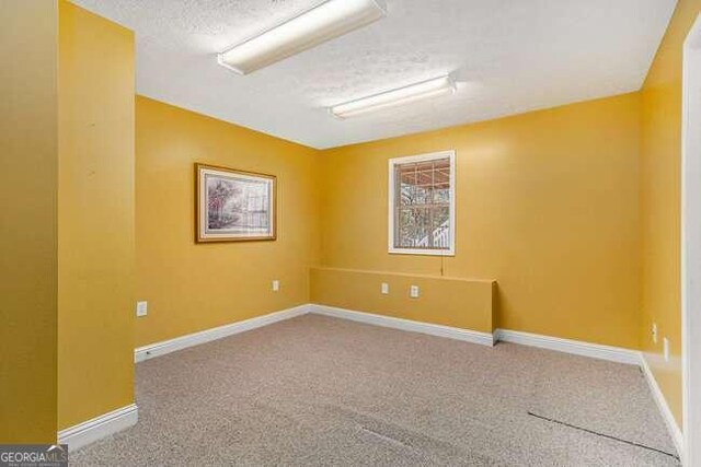 carpeted spare room featuring a textured ceiling