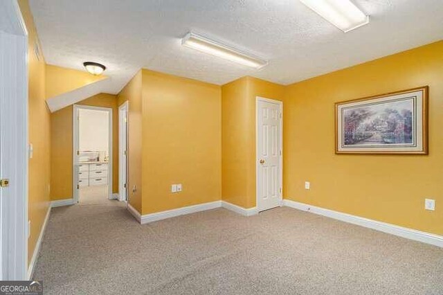 spare room featuring a textured ceiling and light colored carpet