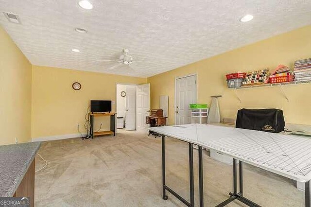 office area featuring a textured ceiling, light colored carpet, and ceiling fan