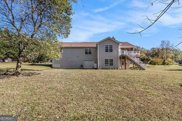 rear view of house featuring a wooden deck and a yard