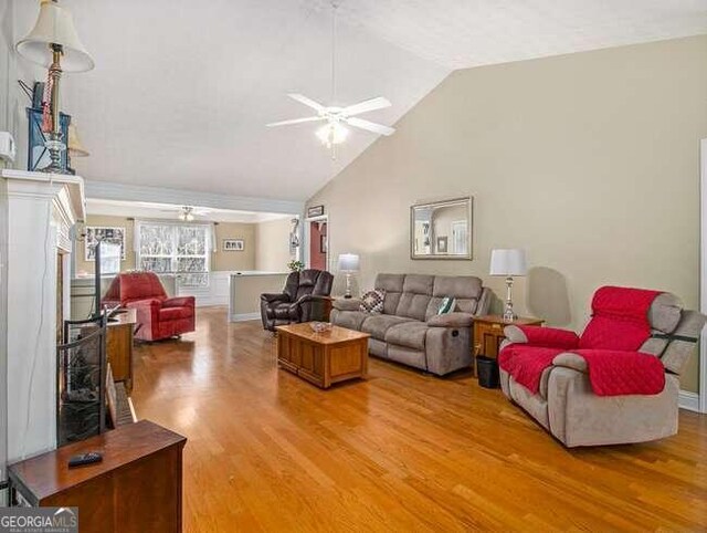 living room featuring ceiling fan, wood-type flooring, and vaulted ceiling