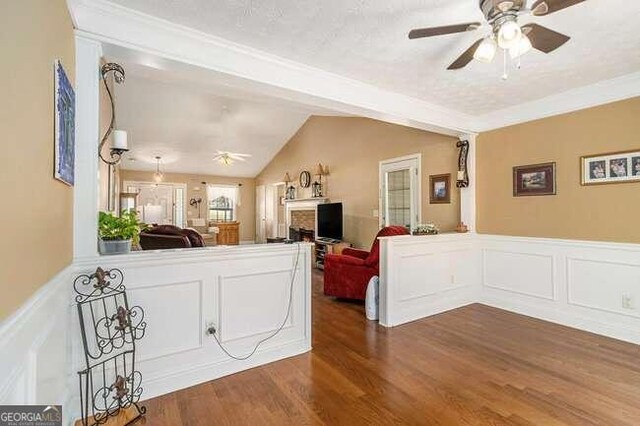 living room with dark hardwood / wood-style flooring, vaulted ceiling, ceiling fan, and crown molding