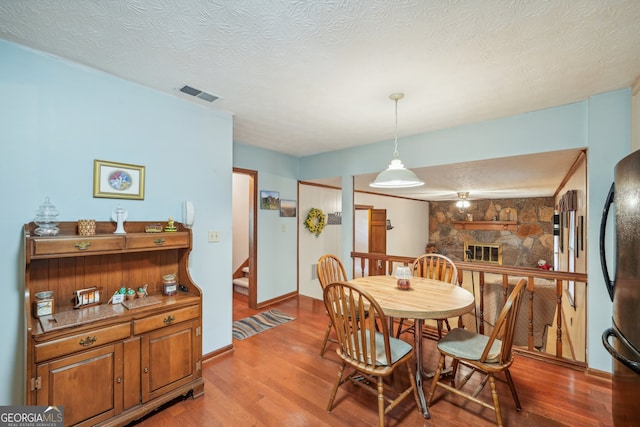 dining room with a fireplace, a textured ceiling, and hardwood / wood-style flooring