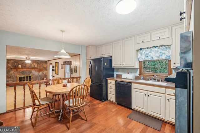 kitchen featuring white cabinetry, sink, pendant lighting, black appliances, and light hardwood / wood-style floors