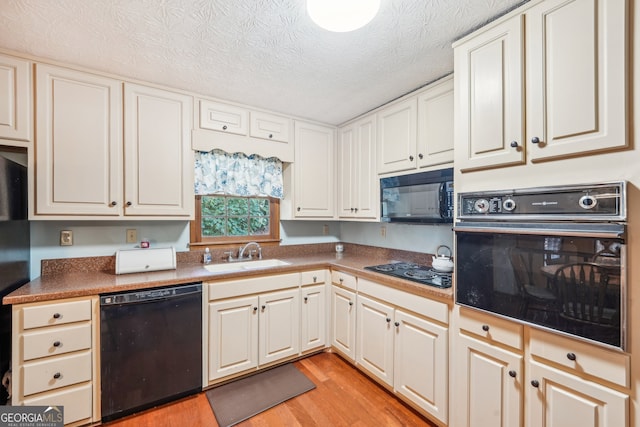 kitchen featuring a textured ceiling, sink, black appliances, white cabinets, and light hardwood / wood-style floors