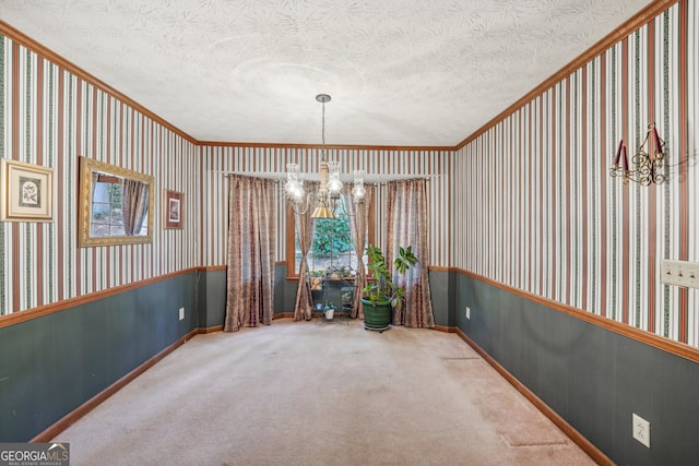 unfurnished dining area with carpet, a textured ceiling, ornamental molding, and a notable chandelier