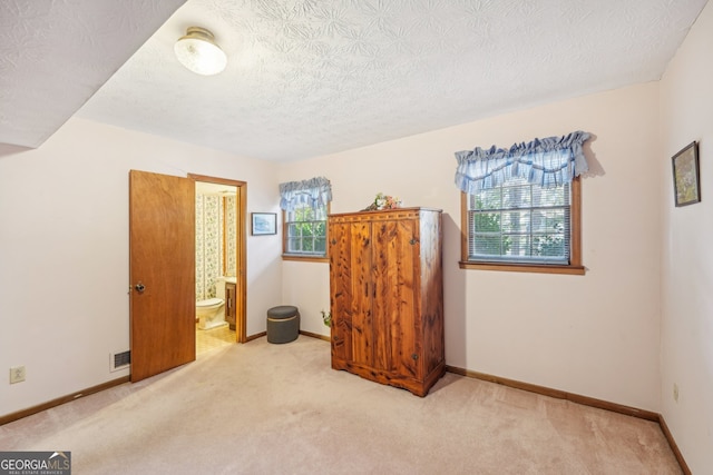 carpeted bedroom featuring connected bathroom and a textured ceiling