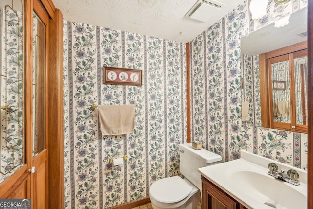 bathroom with vanity, a textured ceiling, and toilet