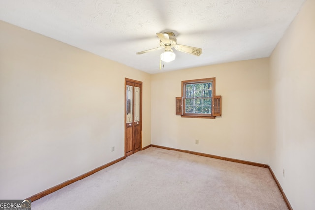 empty room featuring ceiling fan, light carpet, and a textured ceiling