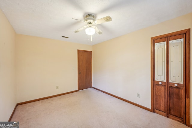 carpeted spare room featuring ceiling fan and a textured ceiling