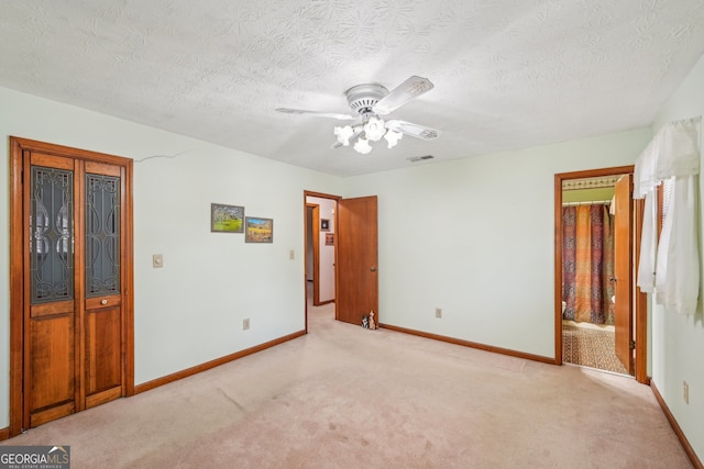 unfurnished bedroom with ceiling fan, light carpet, and a textured ceiling