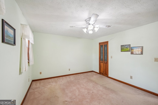 spare room featuring light carpet, ceiling fan, and a textured ceiling