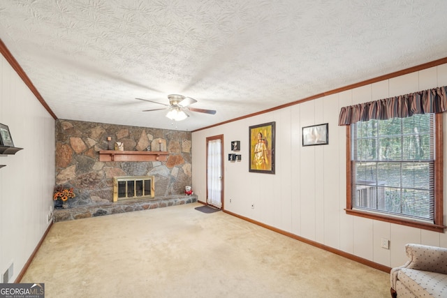 unfurnished living room with a stone fireplace, carpet, a textured ceiling, and ornamental molding