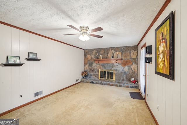 unfurnished living room featuring light carpet, a fireplace, ornamental molding, and ceiling fan