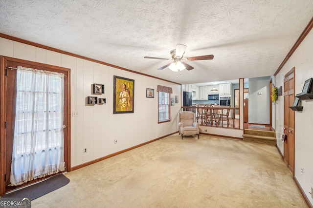 living room with ornamental molding, ceiling fan, light carpet, and a textured ceiling