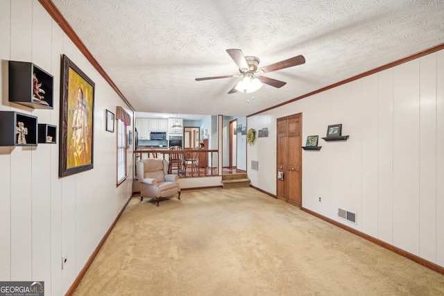 living area featuring light carpet, crown molding, ceiling fan, and a textured ceiling