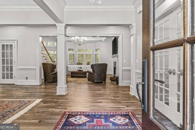 entryway with ornate columns, crown molding, dark hardwood / wood-style flooring, and an inviting chandelier