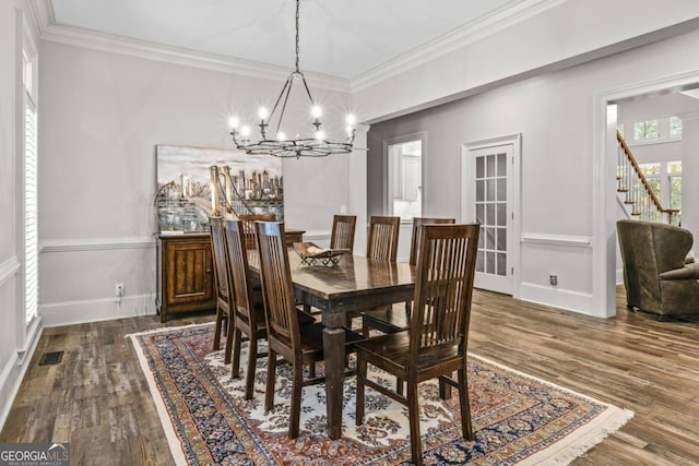 dining space with crown molding, dark hardwood / wood-style floors, and an inviting chandelier