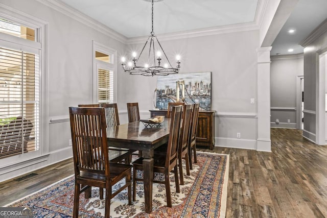 dining space with decorative columns, crown molding, dark wood-type flooring, and an inviting chandelier