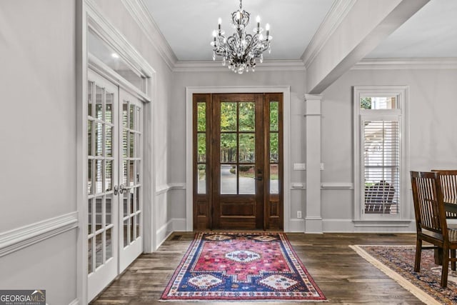 foyer featuring crown molding, dark hardwood / wood-style flooring, a chandelier, and french doors